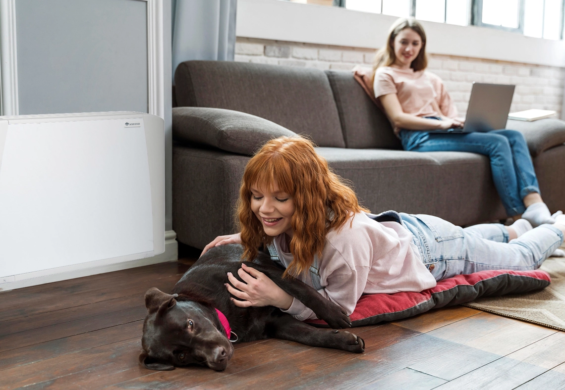 MyCond SEC/F Une fille et son chien à côté dun ventilo-convecteur.
